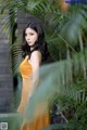 A woman in a yellow dress standing in front of a palm tree.