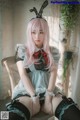 A woman with pink hair sitting on a chair.