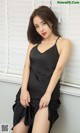 A woman in a black dress sitting on a window sill.