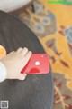 A person holding a red phone on a table.