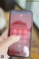 A person holding a red phone with a lock on the screen.