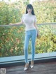 A woman in a white top and blue jeans posing for a picture.