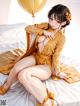 A woman in a yellow kimono sitting on a bed.