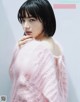 A woman in a pink sweater is posing for a magazine.