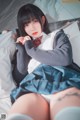 A woman in a school uniform laying on a bed.