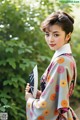 A woman in a kimono holding a fan in her hand.