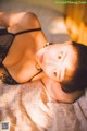 A woman laying on a bed in a black lingerie.