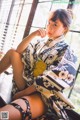 A woman in a kimono sitting on a window sill.